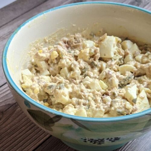 tuna salad in bowl with blue rim on wood table.